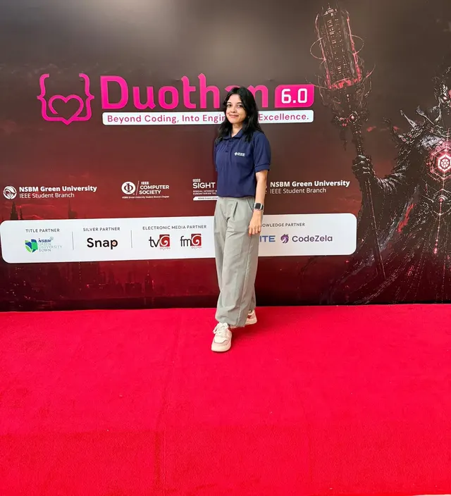 Wathsala in an IEEE polo standing on the red carpet in front of the Duothan 6.0 backdrop
