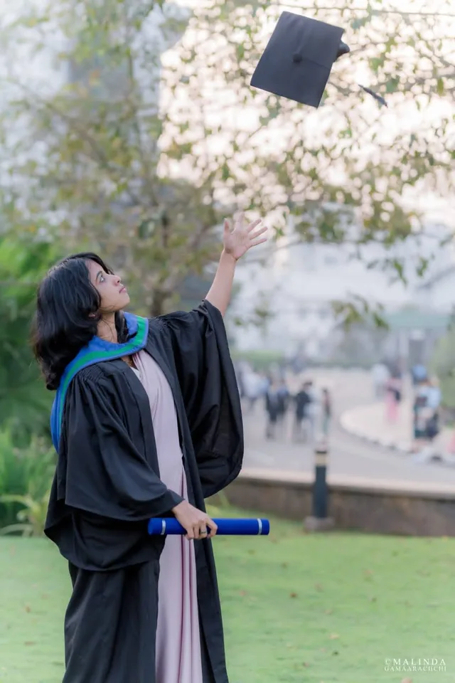Wathsala in a graduation gown on the lawn, throwing her cap into the air and holding her degree scroll