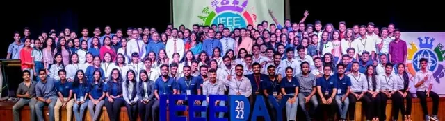 A crowd of well over a hundred students on stage behind large blue IEEE DAY 2022 letters