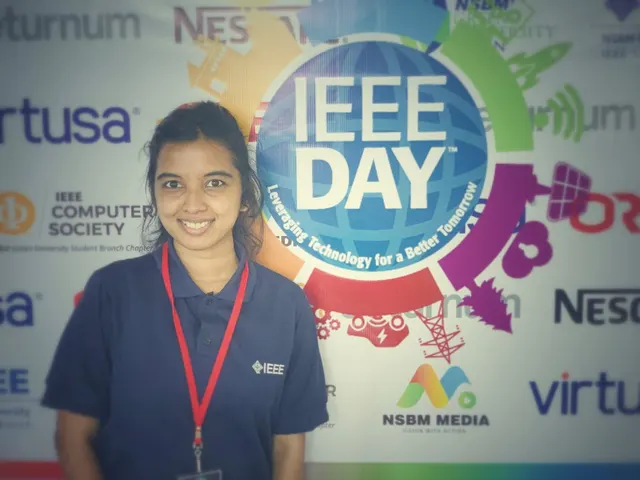 Wathsala in an IEEE polo and lanyard, smiling in front of the IEEE Day backdrop